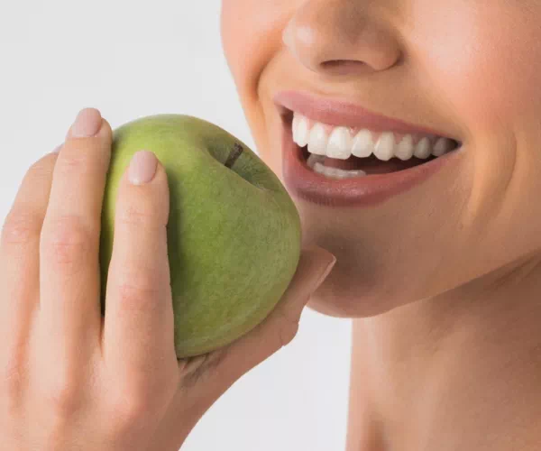 Uśmiechnięta kobieta trzymająca jabłko